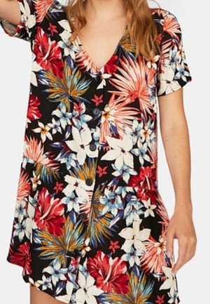 Femme portant une robe noire à manches courtes avec un imprimé de fleurs tropicales éclatantes en rouge, blanc, bleu et orange, et des boutons sur le devant.