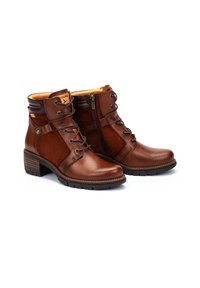 Brown leather ankle boots with a smooth surface, featuring a side zipper, lace-up front, and a rugged sole for traction.