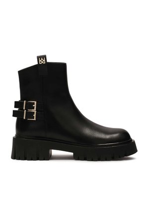 Black leather ankle boots with a chunky sole, featuring two metallic buckles and a pull tab at the back for easy wear.