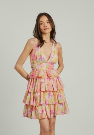 Robe tiered à fleurs rose et jaune avec un décolleté plongeant, en tissu texturé et avec des volants au bas, créant un effet superposé.