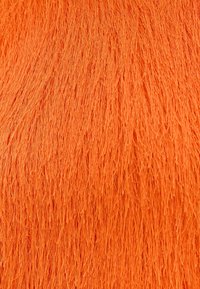 Gros plan de fibres orange vives, denses et fines, superposées de manière dense avec une surface texturée et fibreuse.