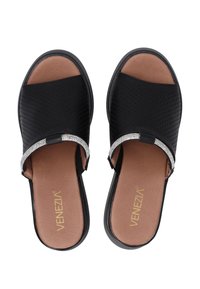 Zwarte slide-sandalen met een geperforeerde lederen bovenkant, een decoratieve strass-accent, en een gevoerde bruine binnenzool. Vlakke rubberen buitenzool.
