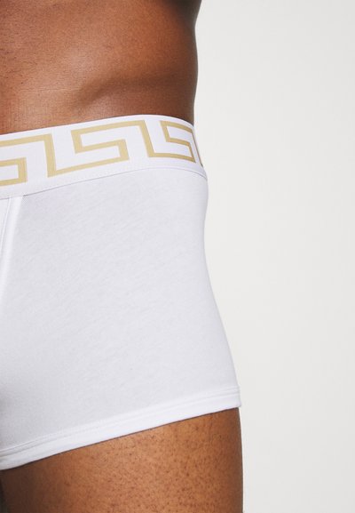 Witte boxer shorts met een gouden geometrisch patroon op de tailleband. Gemaakt van zachte katoen met een aansluitende pasvorm, die een gladde textuur en strakke lijnen toont.