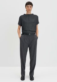 Haut texturé gris foncé à manches courtes, associé à un pantalon taille haute assorti. Une ceinture noire et des chaussures complètent le look.