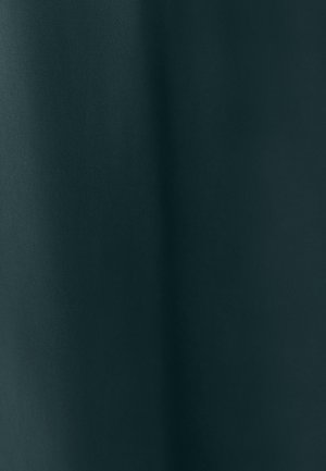 Un tissu texturé vert foncé tombe doucement, mettant en valeur des variations subtiles d'ombre et de lumière, soulignant sa texture lisse et riche.