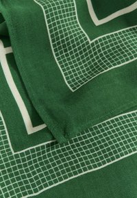 Scarf verde realizzato in morbido tessuto con un motivo geometrico a griglia in bianco. I bordi sono rifiniti in modo ordinato per garantire durabilità.