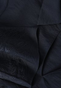 Tissu bleu marine avec un motif paisley subtil et des détails de broderie texturée. Le matériau semble lisse avec un éclat doux.