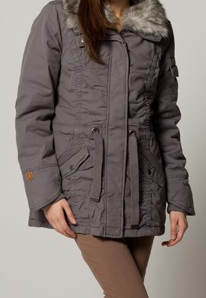 Parka grigia con colletto in pelliccia sintetica, vita regolabile con cordino e chiusura con zip. Ha tasche laterali e tessuto testurizzato.