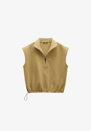 Beżowy bezrękawnik z półzamkiem i regulowanym ściągaczem na dole, wykonany z teksturowanej tkaniny.