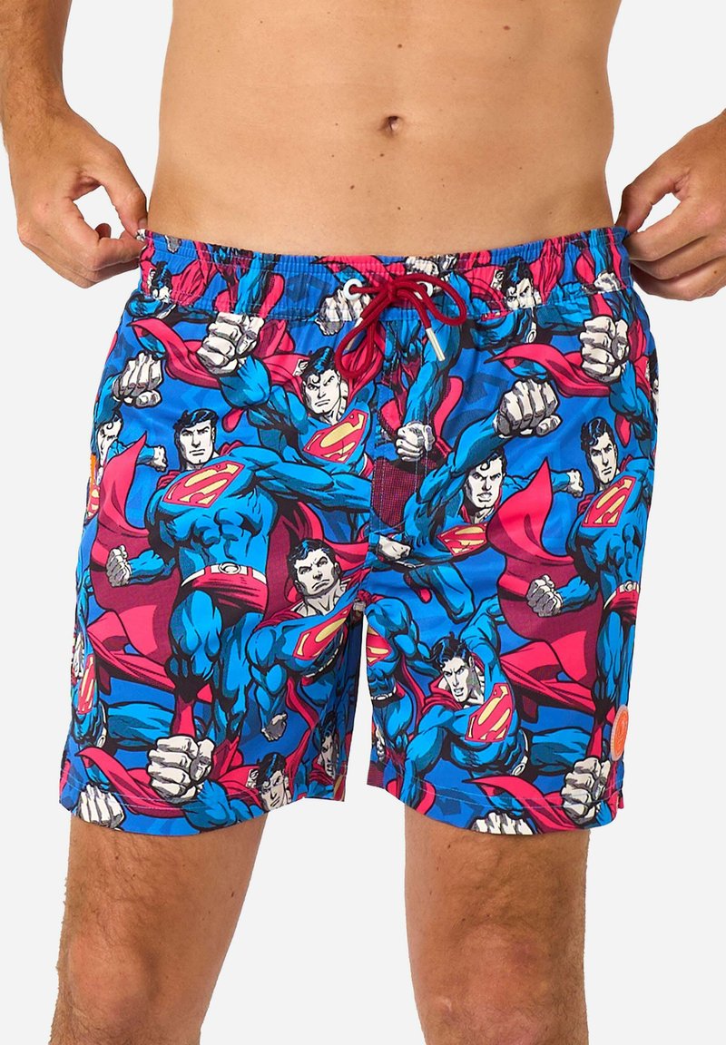 Mėlyni maudymosi šortai su detaliu spausdiniu, vaizduojančiu Superman veikėjus ryškiomis raudonomis ir mėlynomis spalvomis, turi elastingą juosmenį ir raištelį.