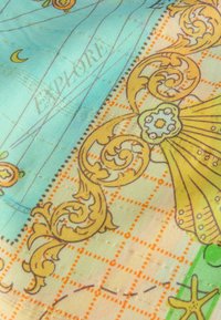 Tessuto colorato con uno sfondo blu e complessi motivi floreali gialli, disegni a griglia e accenti in arancione e verde. Il testo recita "ESPLORA."