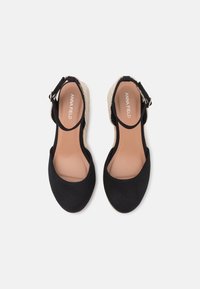 Espadrillas in tessuto nero con cinturino alla caviglia, design a punta tonda e tacco in juta intrecciata. Rivestimento interno liscio di un colore chiaro.