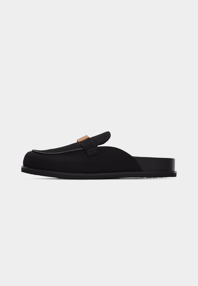Μαύρο loafers χωρίς κορδόνια με επίπεδη σόλα και διακοσμητικό λουράκι με μικρή χρυσή αγκράφα.