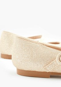 Glittriga beige baletttofflor med rund tå och en liten klack. Syntetmaterial, strukturerad yta och en diskret utskärning.