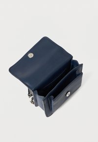 Granatowa skórzana torebka z fakturowaną powierzchnią, zamknięciem na magnes, dwoma przegródkami oraz srebrnymi dodatkami.