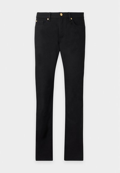 Pantalon noir droit avec boutons dorés et rivets, poches avant et passants de ceinture sur un fond clair uni.