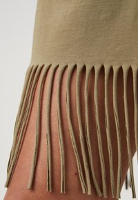 Olivgrön fransad topp med mjuk bomullstextur, som har jämnt fördelade vertikala sprund i nederkant, vilket skapar en lager-effekt.