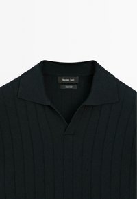 Zwarte katoenen polo met een geribbelde structuur, voorzien van een korte kraag en een V-hals ontwerp, gelabeld met merkdetails bij de hals.