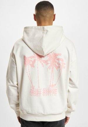 White hoodie with a drawstring hood, featuring a pink palm tree graphic and the words "Just Rinse" on the back. Cotton material and relaxed fit.