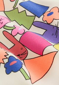 Tela colorida con dibujos de conejos de caricatura, flores y formas geométricas en rosa, morado, azul, verde y naranja sobre un fondo crema.