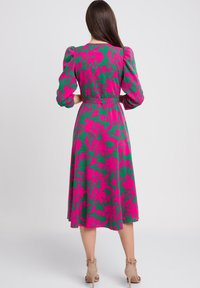 Sukienka o średniej długości z żywym zielonym i różowym wzorem kwiatowym, z bufiastymi rękawami i paskiem w talii. Gładka faktura materiału.