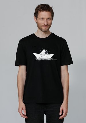 Zwarte katoenen t-shirt met een witte afbeelding van een papieren boot en astronaut, omringd door sterren. Korte mouwen, ronde hals.