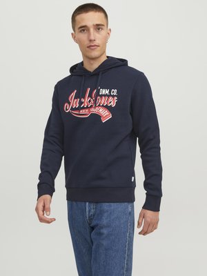 Marineblauwe hoodie met een vooraanstaande graphic in witte en rode tekst, geribbelde boorden en een ontspannen pasvorm. Gemaakt van katoen met een zachte textuur.