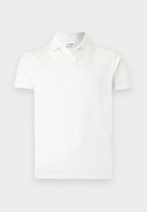 Hvit kortermet poloskjorte med krage og en liten merkelapp inne i nakken med teksten "FILIPPA K", vist på en enkel lys bakgrunn.