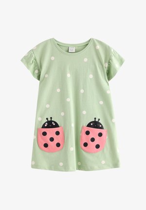 Vestito verde chiaro a maniche corte con pois bianchi, caratterizzato da due tasche rosa frontali con coccinelle sorridenti che spuntano fuori.