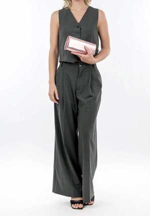 Ärmelloser grauer Overall mit V-Ausschnitt und Knöpfen, Hose mit weitem Bein, kombiniert mit einer metallic-rosafarbenen Clutch und schwarzen Sandalen.
