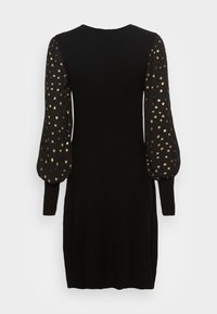 Svart klänning med långa puffärmar i genomskinligt tyg med guldprickigt mönster. Enkel, skräddarsydd design med rund halsringning.