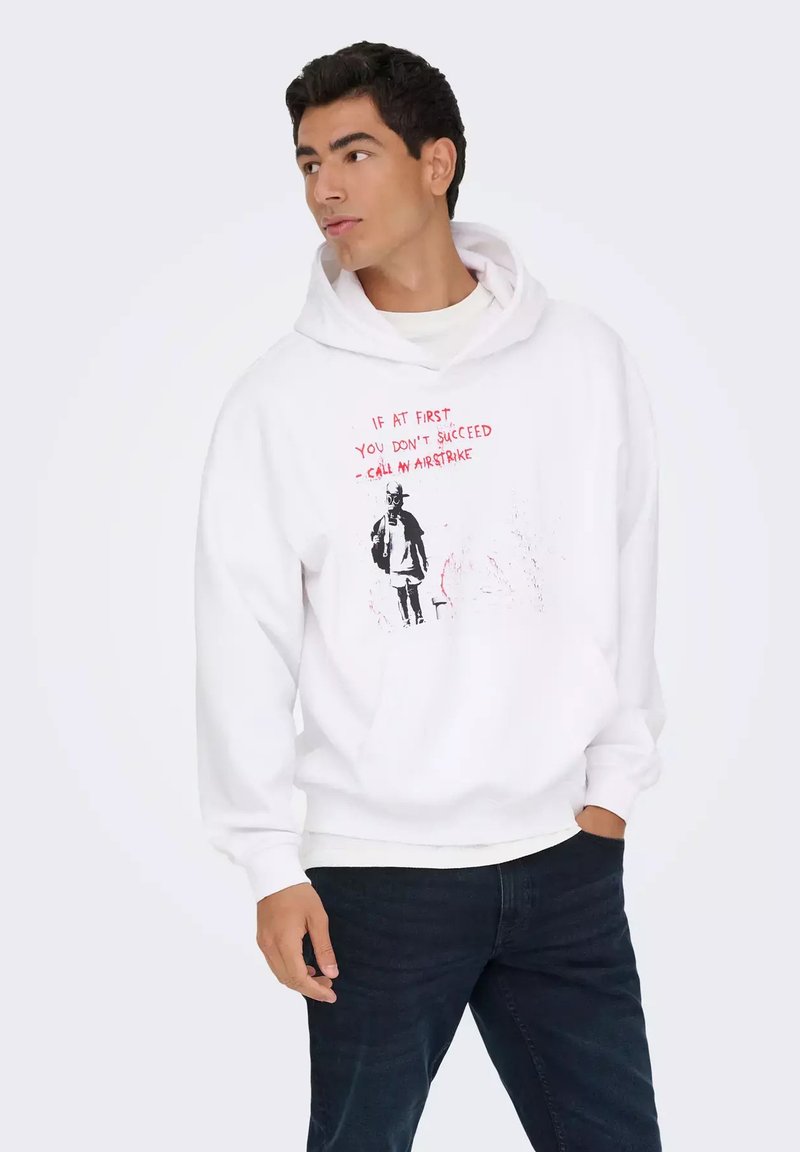 Felpa bianca con cappuccio caratterizzata da una grande stampa grafica in testo nero e rosso. Il design include una figura che tiene un microfono con un testo stilizzato.
