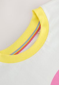 Valge t-särk ümmarguse kollase kraega, millel on roosa, sinine, oranž ja roheline triibuline muster. Pehme puuvillane materjal. Reguleeritav sobivus.