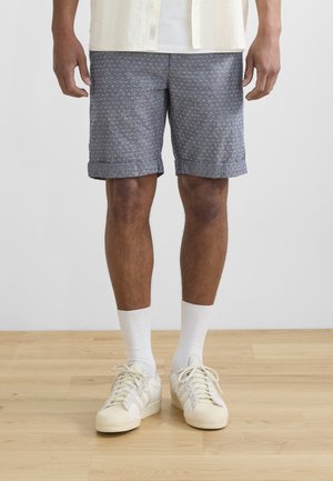Gray patterned shorts with rolled cuffs, paired with white crew socks and beige sneakers. The fabric has a textured appearance.