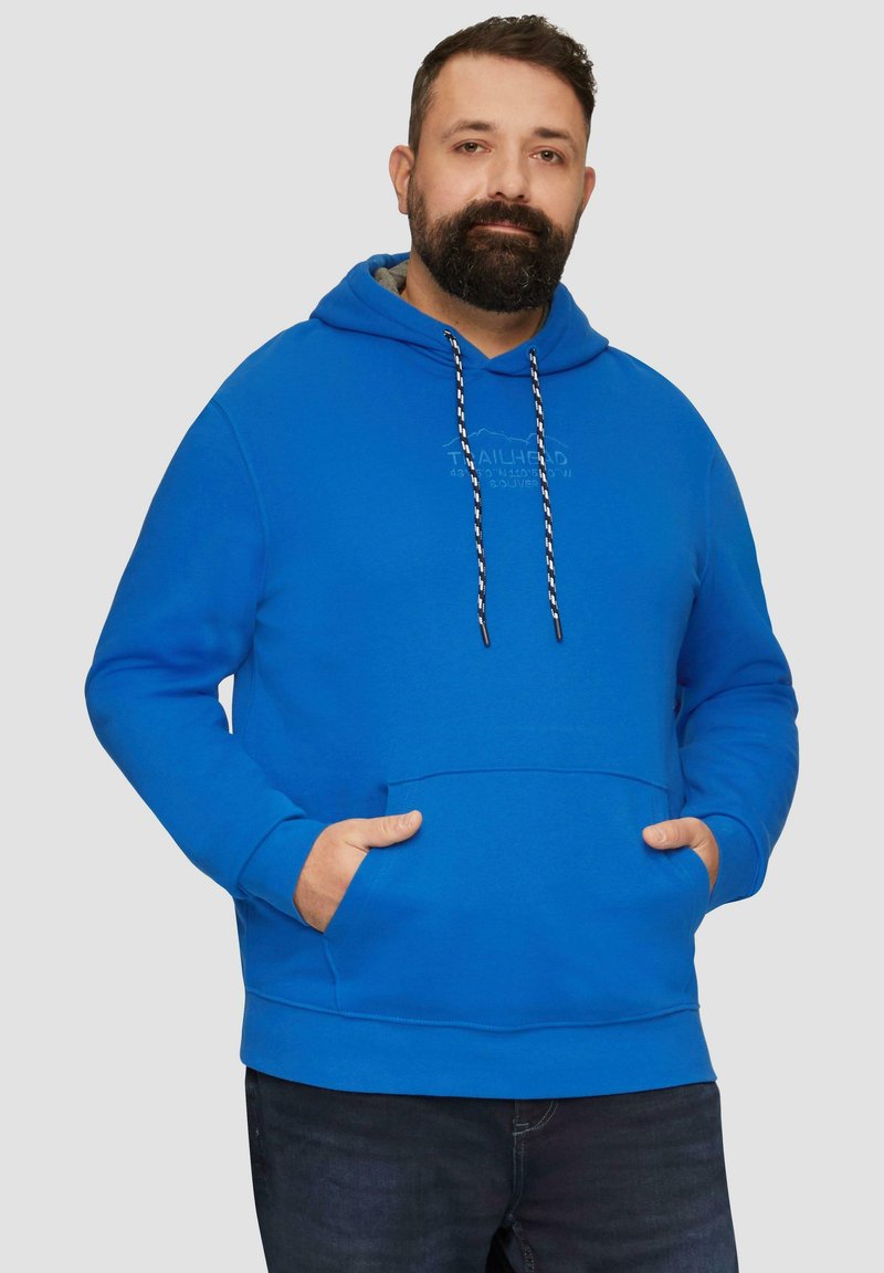 Niebieska bluza z kapturem, wykonana z miękkiego materiału, posiadająca przednią kieszeń kangurkę, regulowany kaptur z troczkami oraz subtelne logo. Posiada długie rękawy i luźny krój.