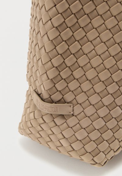 Πλεκτή τσάντα ώμου σε μπεζ χρώμα με ανάγλυφη εξωτερική επιφάνεια, διαθέτει ορθογώνιο σχήμα και λεπτομέρεια με ανάγλυφη ετικέτα. Ανθεκτικό υλικό με εκλεπτυσμένο σχεδιασμό.