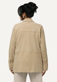 Beige Wildlederjacke mit lässiger Passform, langen Ärmeln und knöpfbaren Manschetten. Saubere Linien und eine glatte Textur. Rückansicht hervorgehoben.