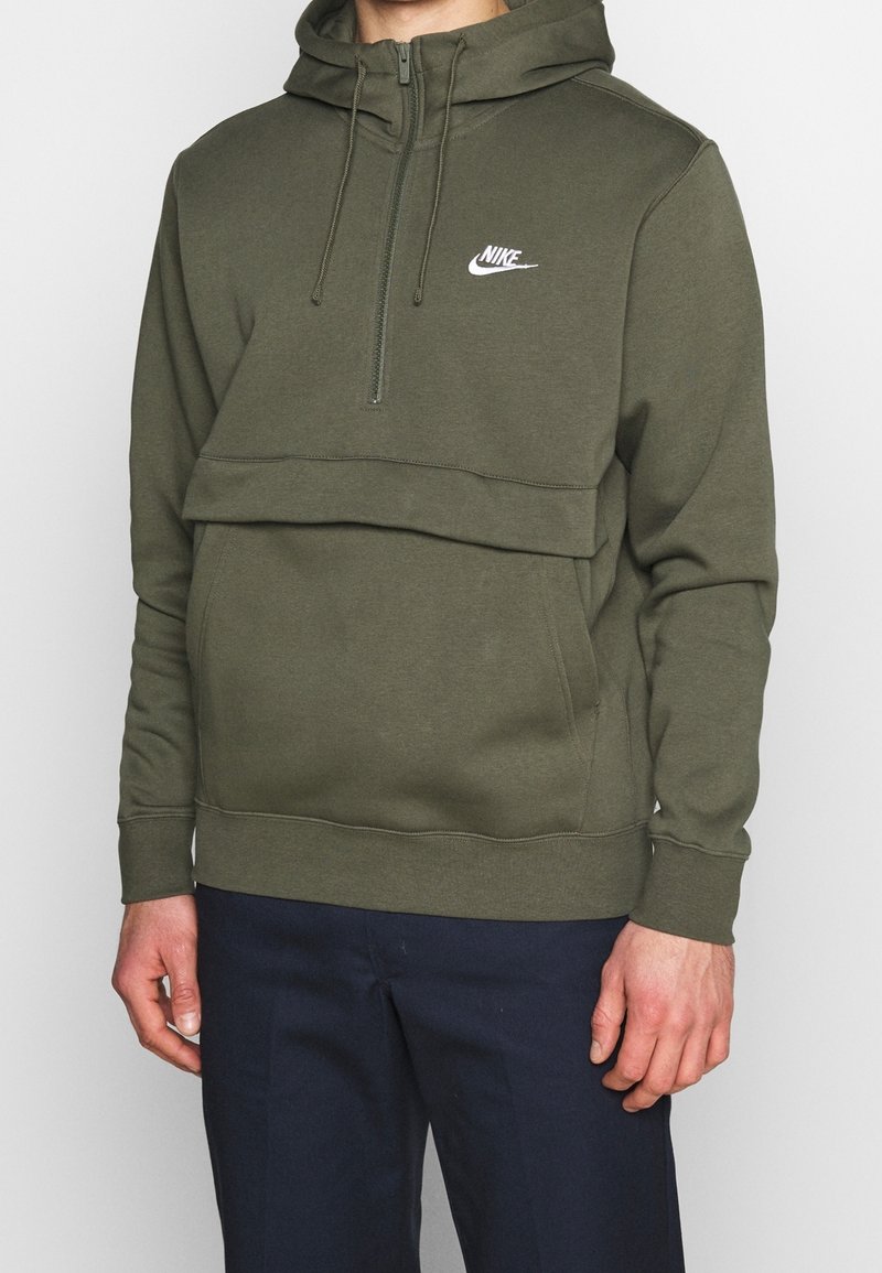 Olivgrön zip-up hoodie i mjukt tyg, med en kenguruficka, justerbar dragsko och vit Nike-logga på bröstet.