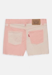 Pantalones cortos de mezclilla bicolor en rosa y beige, con dobladillo deshilachado, dos bolsillos traseros y una etiqueta de cuero marrón en la cintura.