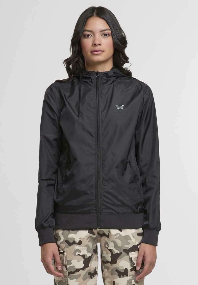 Black zip-up jacket in lightweight fabric with a hood, elastic cuffs, and waistband. Features subtle butterfly logo on the chest.