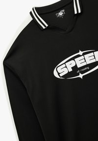 Czarna koszula z długim rękawem z białymi paskami na kołnierzu, z wyraźnym białym logo "SPEED" i wzorzystym materiałem.