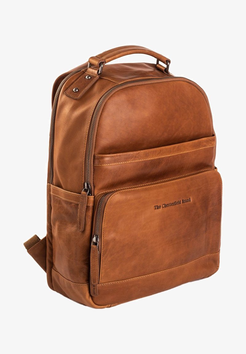 Ruskea nahkainen reppu, jossa on sileä pinta, yläkahva, vetoketjullisia osastoja ja hienovarainen brändäys edessä.