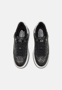 Černé tenisky s texturovanou textilií, která obsahuje jemný vzor loga. Design na šněrování, s bílou podrážkou a kontrastními černými akcenty.