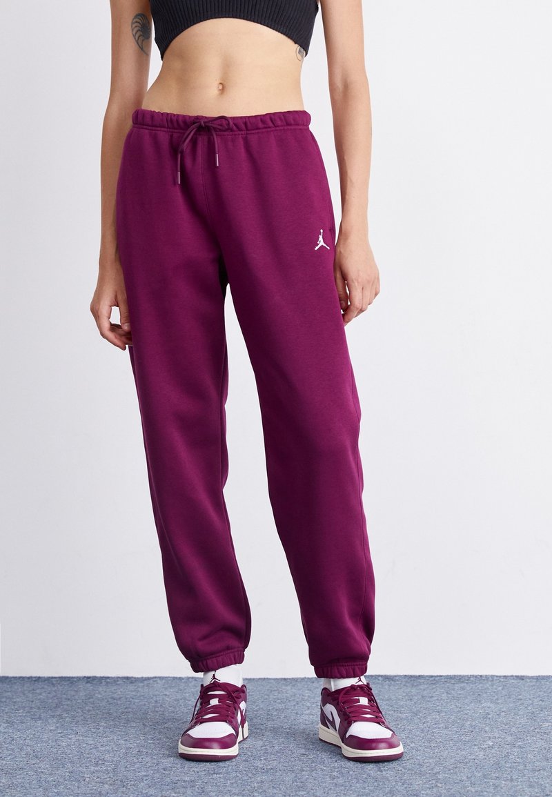 Paarse trainingsbroek met een elastische tailleband en enkelboorden, met een wit Jordan-logo op de linker bovenbeen, gemaakt van zachte stof.