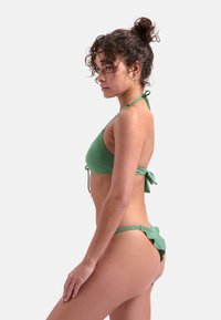 Zelená bikiny souprava s texturovaným povrchem, designem na zavazování za krk a vázacími detaily na vrchu a vzadu. Nastavitelný, minimalistický design.
