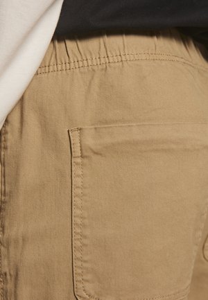 Pantalones cortos cargo de color marrón claro con cinturilla elástica, bolsillos laterales y una tela suave y duradera con una sutil textura de tejido.