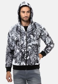 Hoodie in Schwarz und Weiß mit Reißverschluss, verziert mit detaillierten Löwen- und Tribal-Mustern, ausgestattet mit schwarzen Bündchen und einer Kapuze mit Kordelzug.