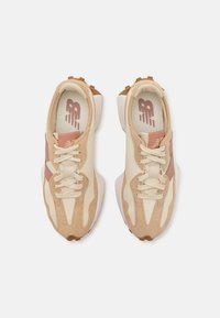 Paire de baskets de sport beiges et roses avec lacets, détails en daim et tissu, vue de dessus sur fond blanc.