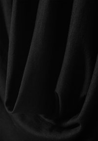 Tela negra con una textura suave dispuesta en pliegues, mostrando un tejido fino. El material parece suave y ligero.