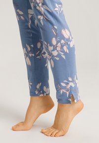 Leggings azules con un patrón floral en blanco y rojo, con aberturas en los laterales del dobladillo para un detalle adicional y mayor flexibilidad.